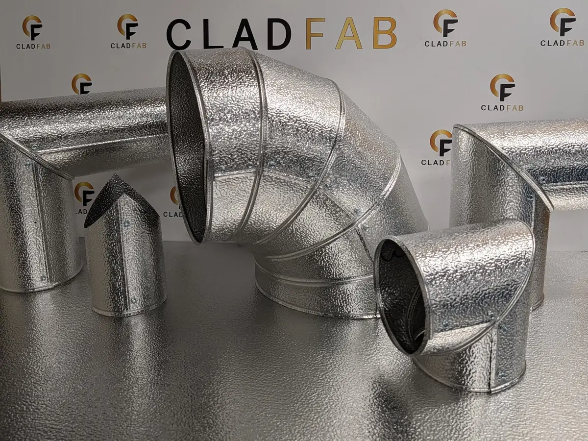 A family of CladFab aluminium cladding fittings — gored bend, elbows and mitred end caps — on the workshop counter