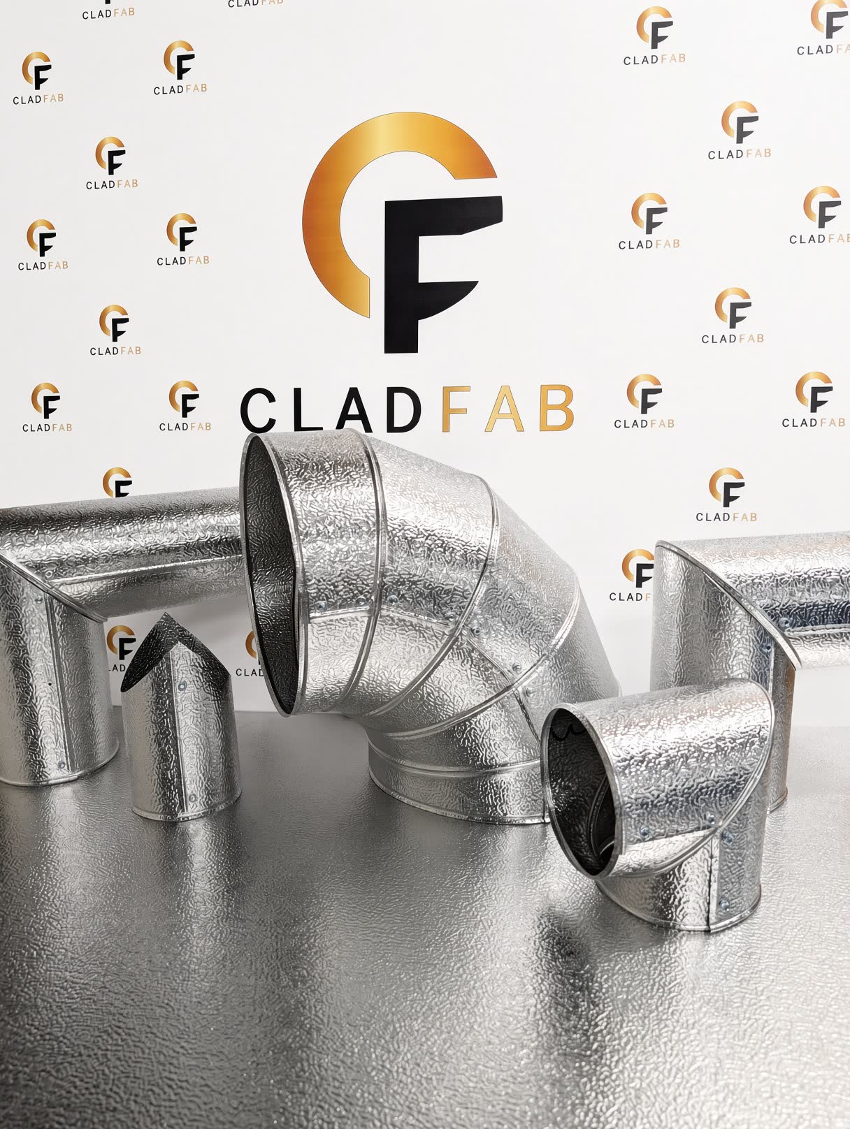 A group of stucco-embossed aluminium cladding fittings made by CladFab, against the CladFab backdrop
