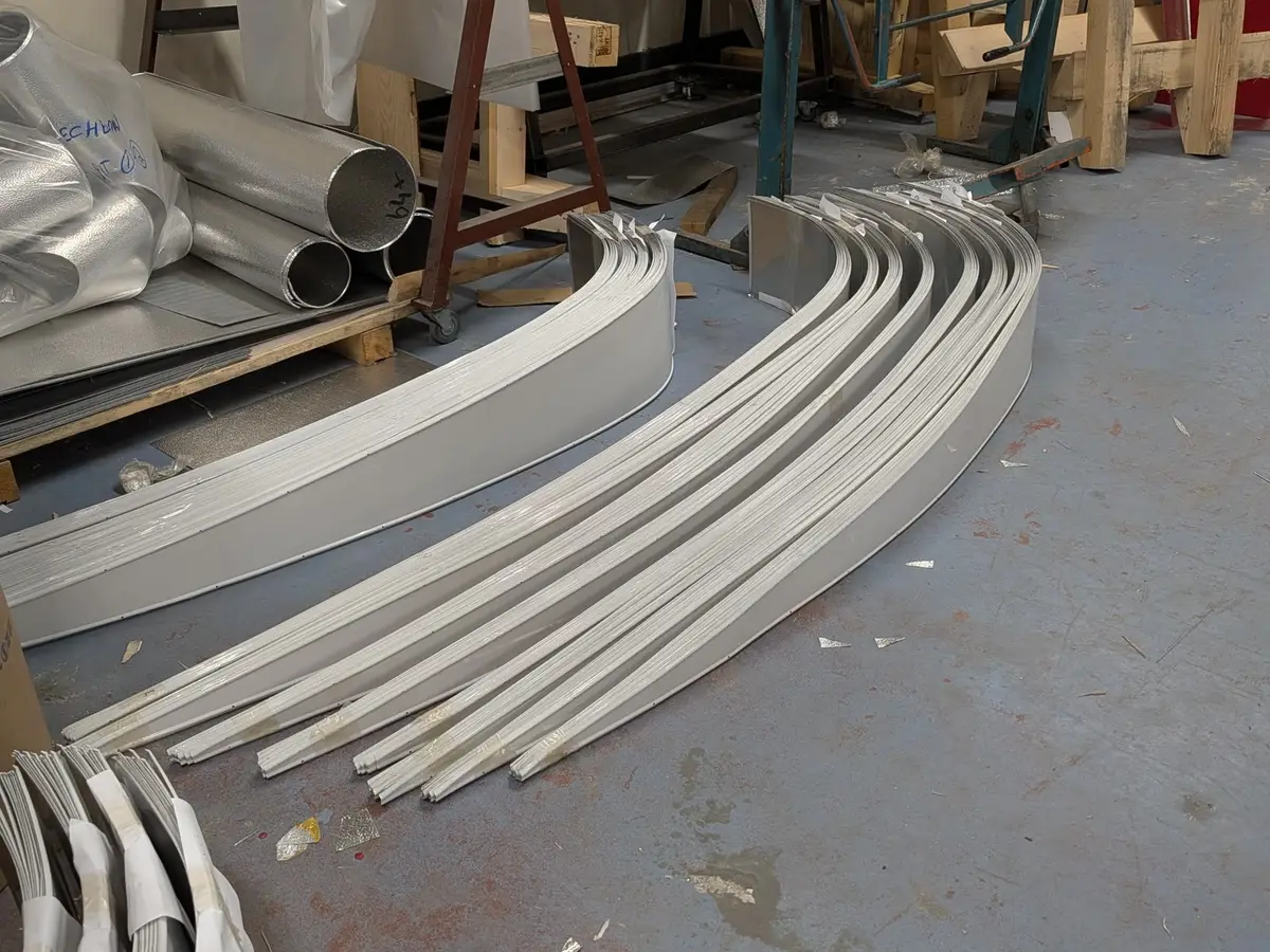 CladFab workshop floor with rolled colour-coated cladding sections beside the rolling machines